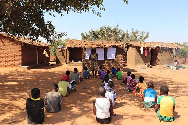 A classroom set up under a tree shelter